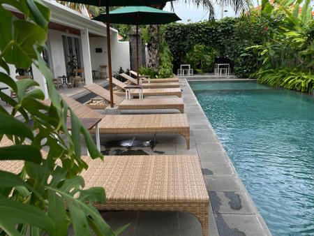 Swimming pool with sun loungers and umbrellas in tropical resort