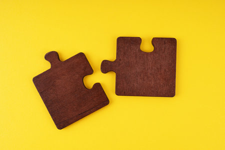 Two wooden jigsaw puzzles on yellow background
