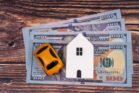 Side hustle concept. Close up of bank notes and property toys on wooden backgroundの写真素材