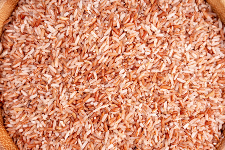 Raw brown whole rice in a bowl over wooden table.の写真素材