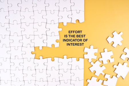 EFFORT IS THE BEST INDICATOR OF INTEREST written on yellow background. With jigsaw puzzles around the phraseの写真素材