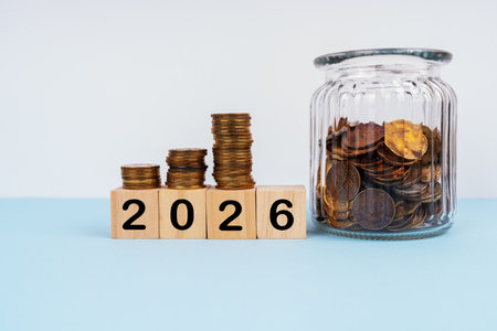 2026 written on wood blocks with stacks of coins. New Year plan concept