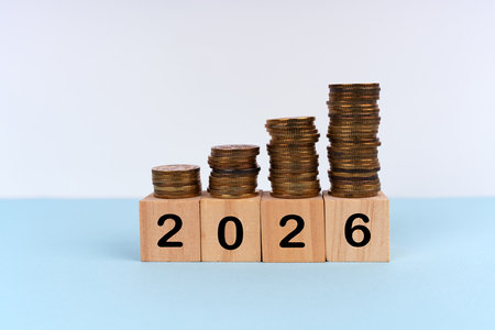 2026 written on wood blocks with stacks of coins. New Year plan concept