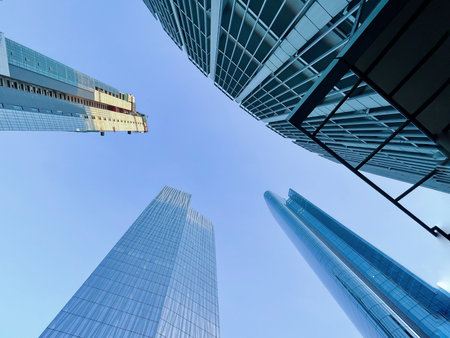 Low-angle view of modern skyscrapers and office towers in Makati City, Metro Manila, Philippines. The image shows glass buildings reflecting the blue sky.の写真素材