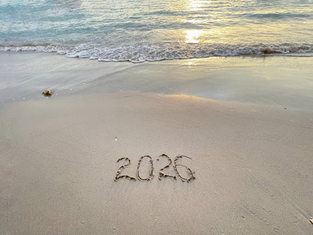 2026 written on the beach sand with a beautiful sunset view. New Year concept.