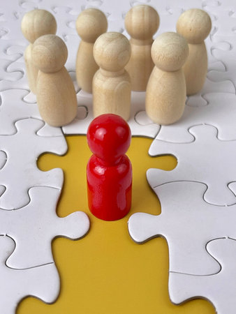 Leadership concept with a red figure standing apart from a group on puzzle pieces.の写真素材