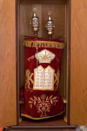 Sefer Torah covered in a red dress and adorned with brass and silver waiting her turn to dance with the faithful.の写真素材