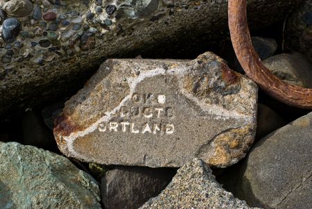 Crumbling remains of a concrete brick complete with stamped letters to identify the manufacturer lies among the debris used to secure a stretch of sandy beach.の写真素材