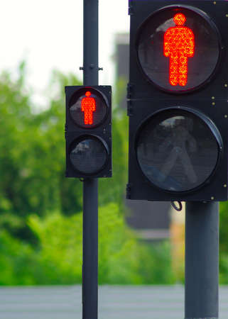 image of two red traffic lights on the background of treesの写真素材