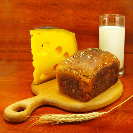 image of a glass of milk, bread on the board, spike and cheeseの写真素材