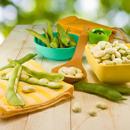 image of young beans in pods on the table on a green backgroundの写真素材
