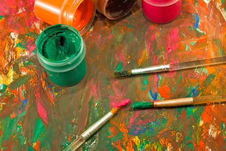 image of  different paints and three brushes closeup