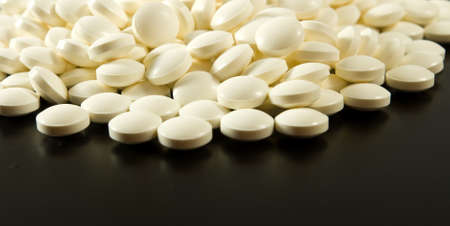 white pills on a black background closeup