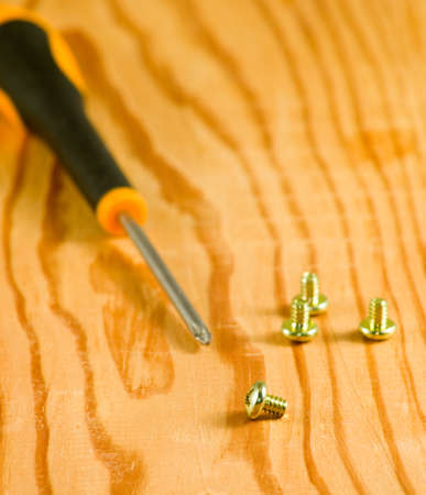 image of screws and screwdriver on a wooden table closeupの写真素材