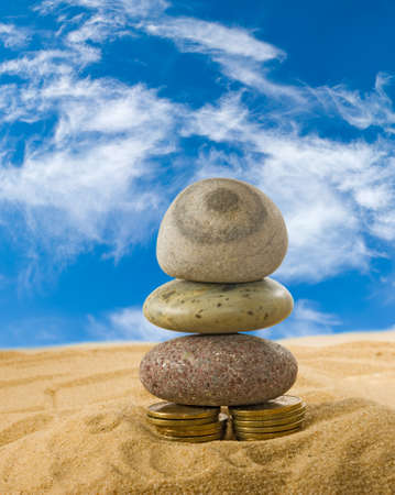 image of coins and stones on the sand closeupの写真素材