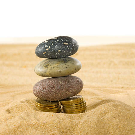 image of coins and stones on the sand closeupの写真素材