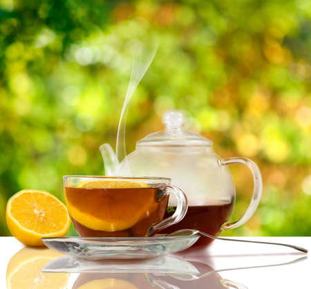 image of cups with tea and lemon on a green background close-upの写真素材
