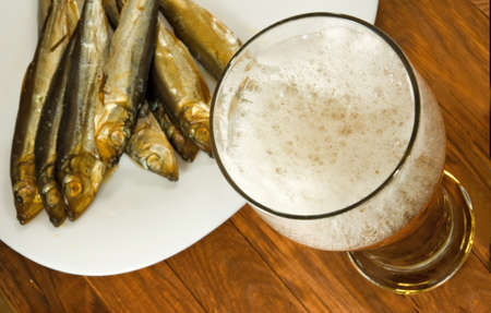 image of a glass of beer and dried fish on a plateの写真素材