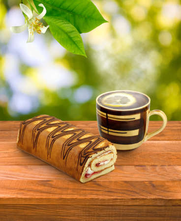 cup of tea, lemon and roll on a tableの写真素材