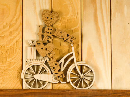 Image of decorative little man on a bicycle on wooden boards background.Wooden man as a symbol of love and a festive mood.の写真素材