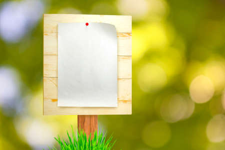 image of the paper sheet on wooden board.Empty blank on blurred green background in the park.Empty...
