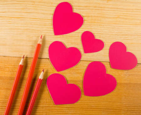 image of envelopes, notebooks, pencils, and paper hearts on a wooden table close-upの写真素材