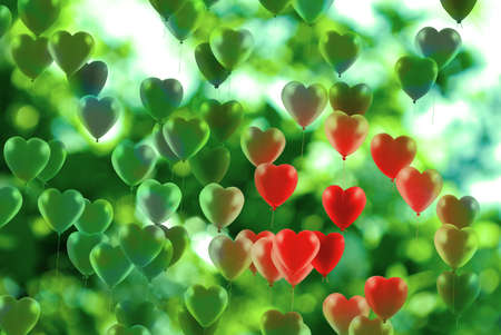 many balloons made in the form of stylized hearts fly on a green backgroundの写真素材