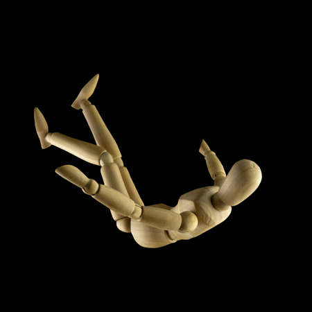 Image of falling wooden manikin on black background