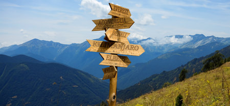 Image of a wooden pointer with directions to mountain peaks with indications of the height of the mountains and the distances to themの写真素材