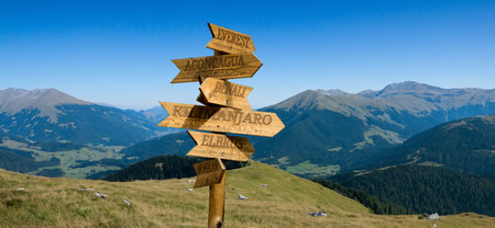 Image of a wooden pointer with directions to mountain peaks with indications of the height of the mountains and the distances to themの写真素材