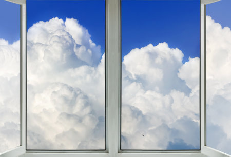 A panoramic view of white cumulus clouds through a window on a bright summer day.