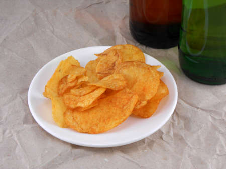 Beer bottles and potato chips on white plate