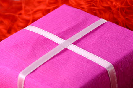 gift box with white ribbon on red backgroundの写真素材