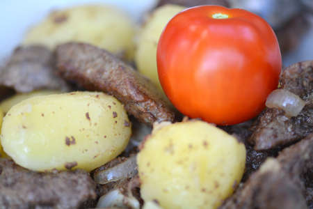 Fried pork liver with tomatoes and potatoesの写真素材