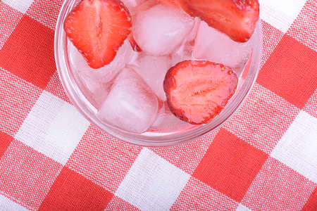 A slice of red strawberry on glass plate in party theme backgroundの写真素材