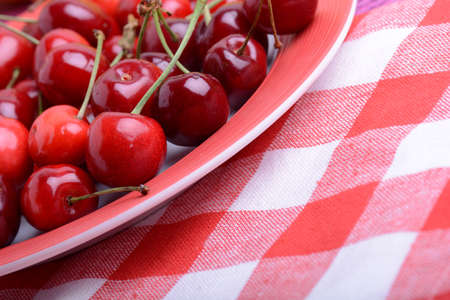 Sweet cherries in bowl on red and white material close upの写真素材