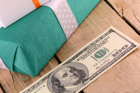 Dollars money along with a gift, a symbol of the crisis, venality, hoarding and wealth. American money on wooden background.の写真素材