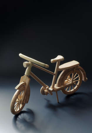 Bicycle small wooden toy model. Dark background with wheel shadows.の写真素材