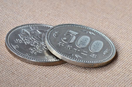 Two 500 japanese Yen coins on oriental beige fabric as backgroundの写真素材