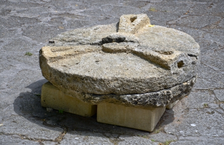 Ancient hand operated millstone on  pavementの写真素材