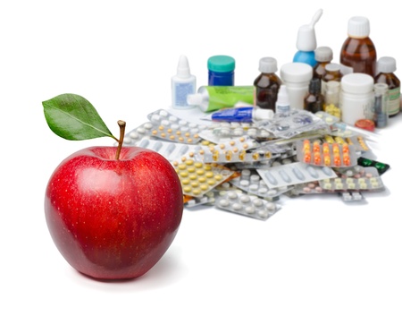Red apple in front of a large pile of medicines. Healthy lifestyle concept.の写真素材