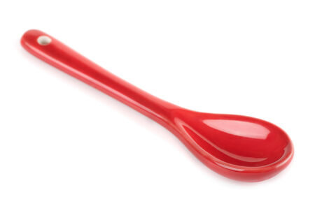 Single red porcelain spoon isolated on whiteの写真素材