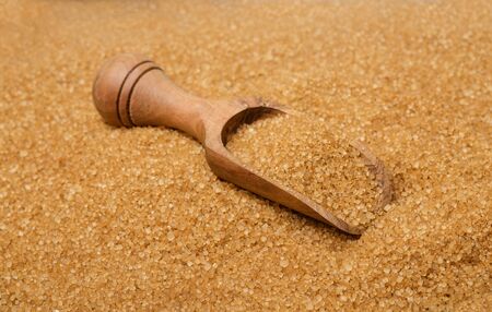 Wooden scoop on brown sugarの写真素材