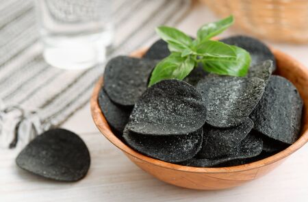 Black spicy potato chips in wooden  bowlの写真素材