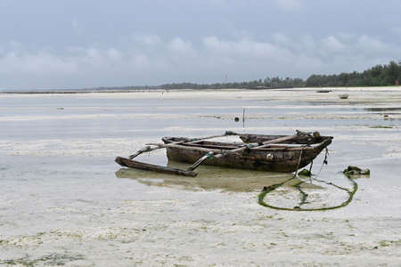 Old wooden fishing boat at low tide in the Indian ocean, Zanzibar island