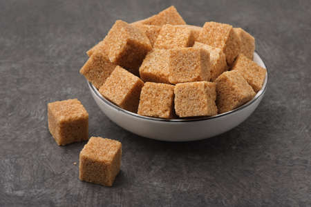 Brown unrefined cane sugar cubes on dark backgroundの写真素材