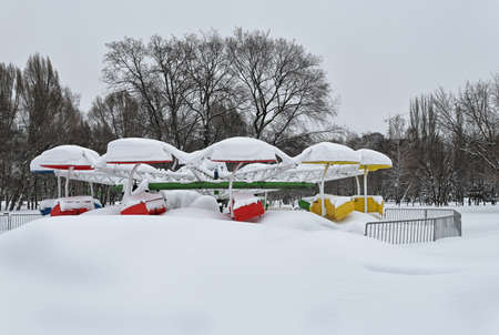 Old snow covered carousel in snowy urban park on gloomy winter dayの写真素材