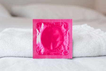 Pink condom on white towels and white bed, white backgroundの写真素材