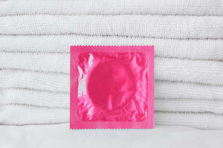 Pink condom on white towels and white bed, white backgroundの写真素材