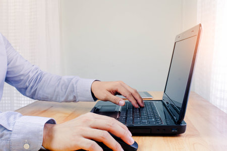 Young man working on computer notebook at table indoors, closeup. Banner design.Business technology...